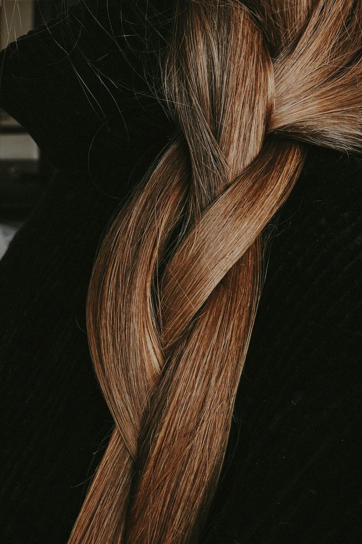 Thick chestnut braid falling over a black top, seen close up
