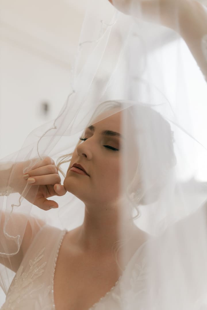 Bride with closed eyes framed by a drift of white tulle