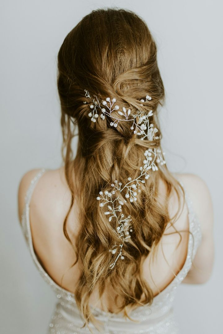 Loose bridal waves threaded with a pearl and crystal hair vine, seen from behind