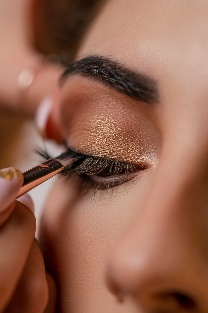 Lashes being applied to an eye finished in shimmering bronze shadow