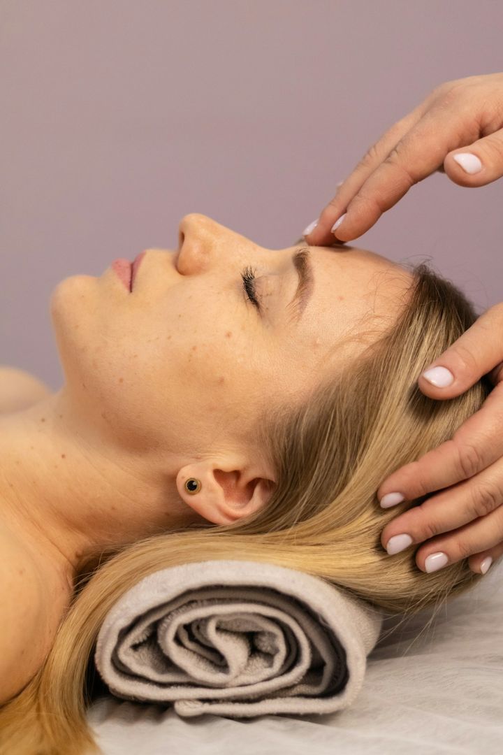Therapist's hands resting at a guest's temples during a facial massage