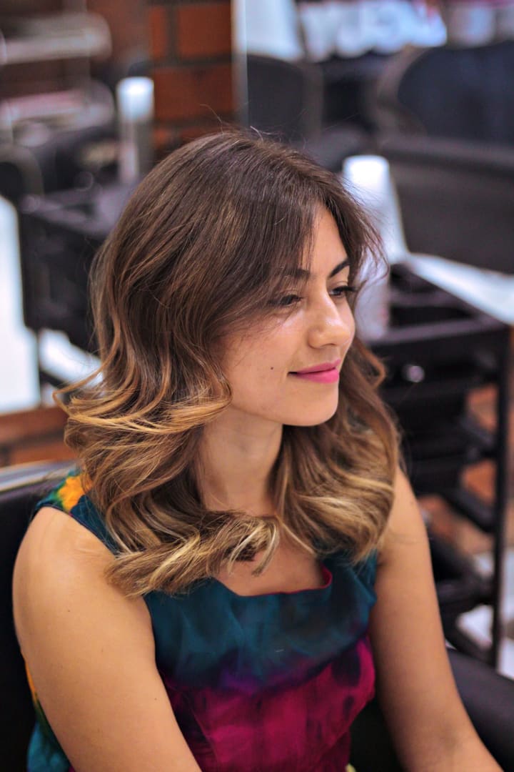 Shoulder-length brunette waves with soft caramel ends, seen in profile