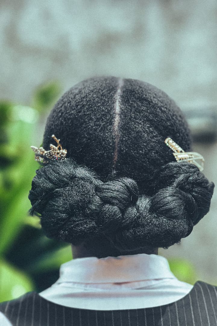 Braided low bun finished with gold leaf hairpins, seen from behind