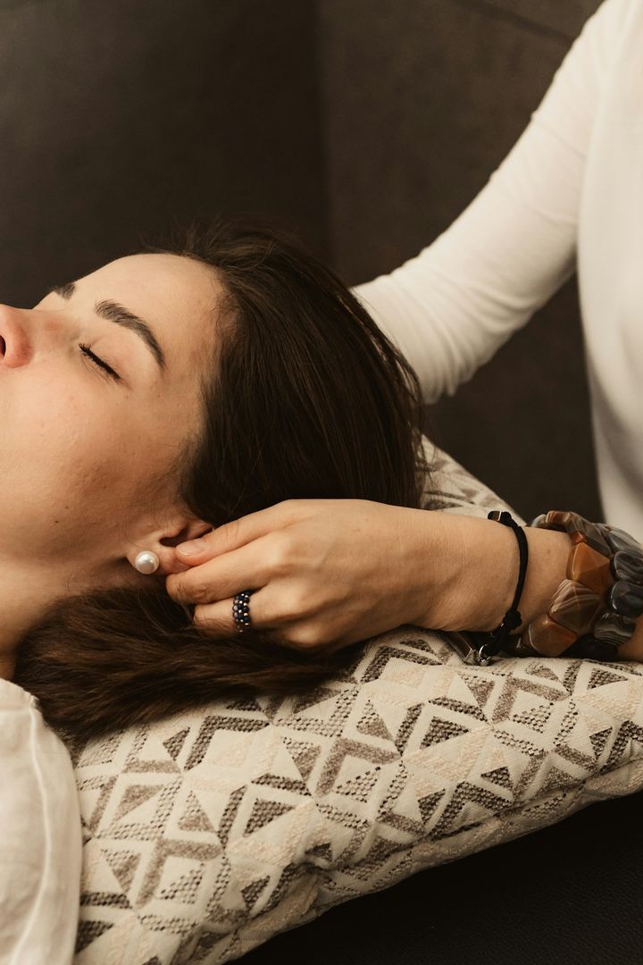 Guest with closed eyes receiving a head massage on a patterned cushion