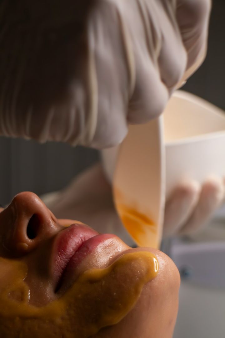 Golden honey mask being brushed along a guest's jaw