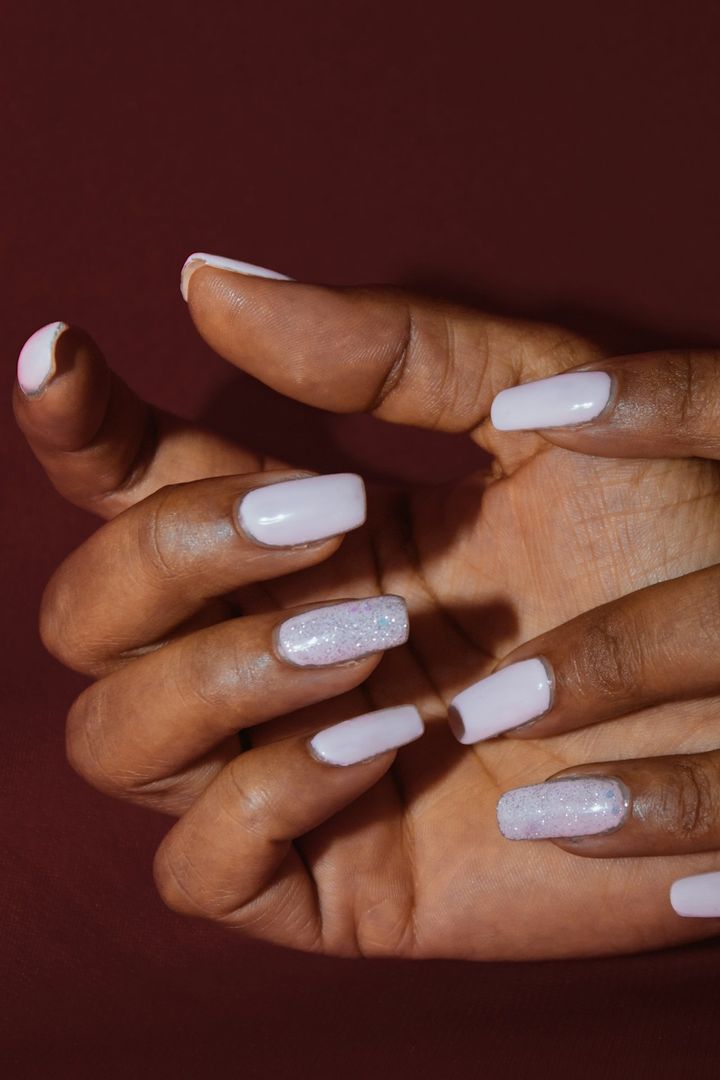 Ivory square nails on folded hands against a deep wine backdrop