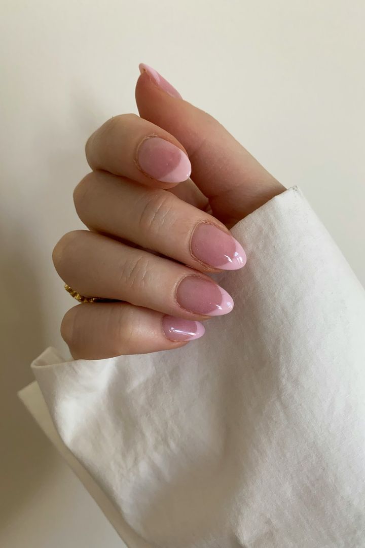 Sheer pink almond nails resting on a folded white cloth