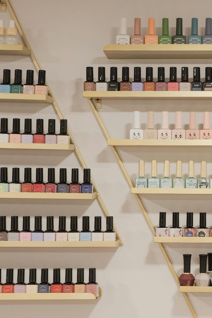 Wall of nail polish bottles arranged on slim wooden shelves