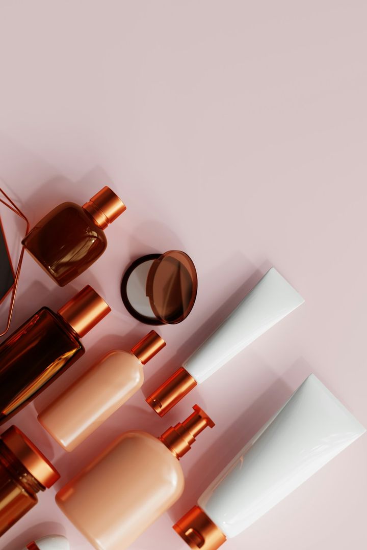 Rose-gold skincare and makeup bottles laid out on a blush surface