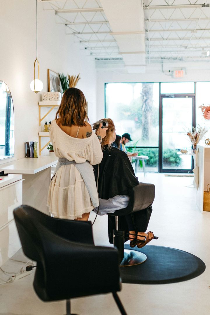 Stylist working on a guest's hair in a bright, airy salon