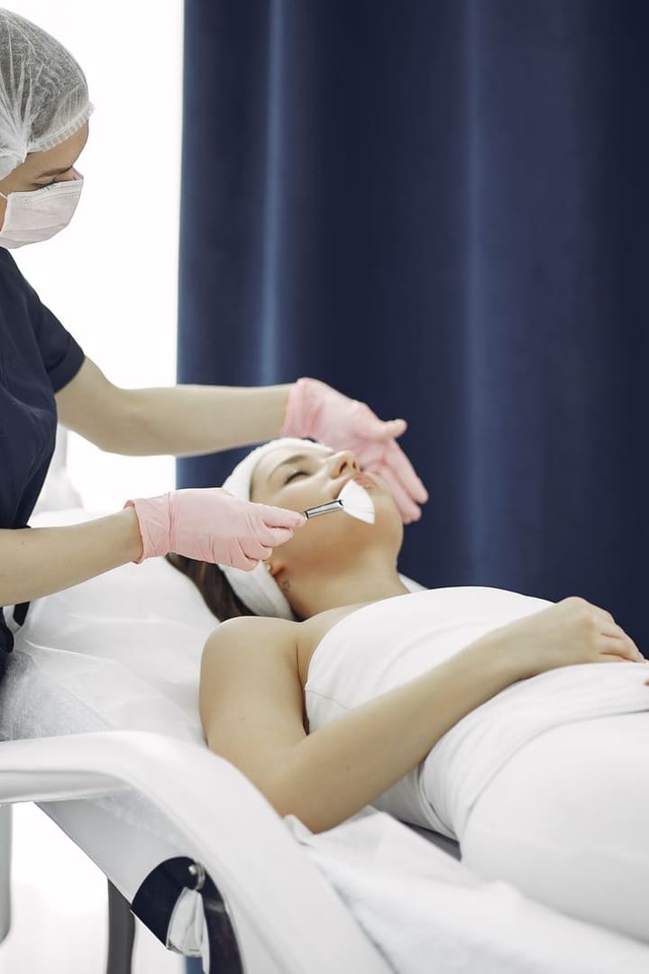 Aesthetician applying a mask with a brush to a guest wrapped in white towels