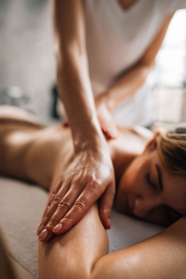 Therapist working warm oil along a guest's upper arm