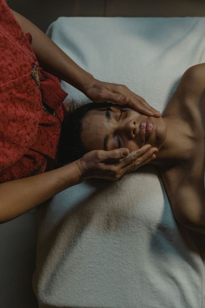 Hands cradling a guest's forehead and jaw during a head massage