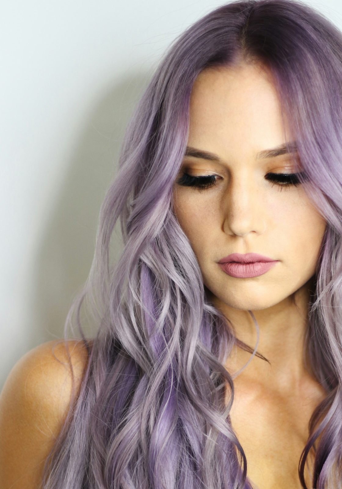 Long lilac waves framing a face with soft pink makeup