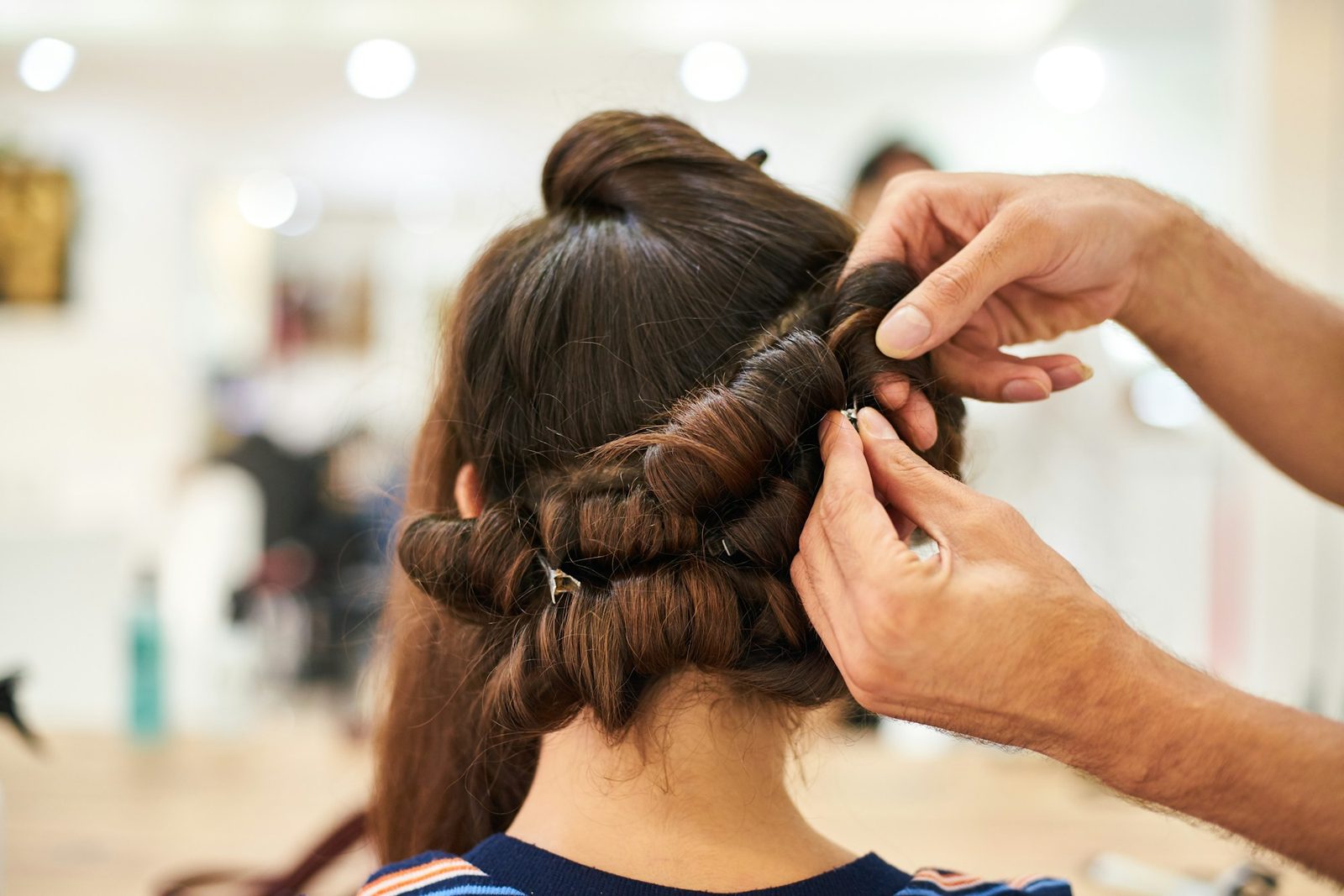Stylist pinning rolled sections of an updo into place