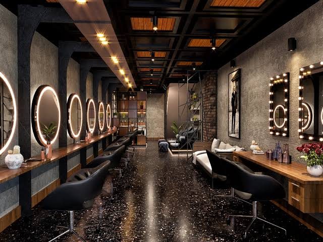 Row of backlit round mirrors and black styling chairs along a stone wall
