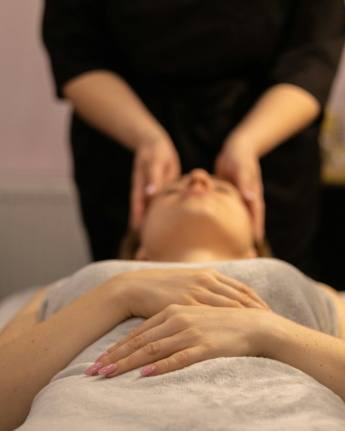 Therapist giving a relaxed client a calming facial massage